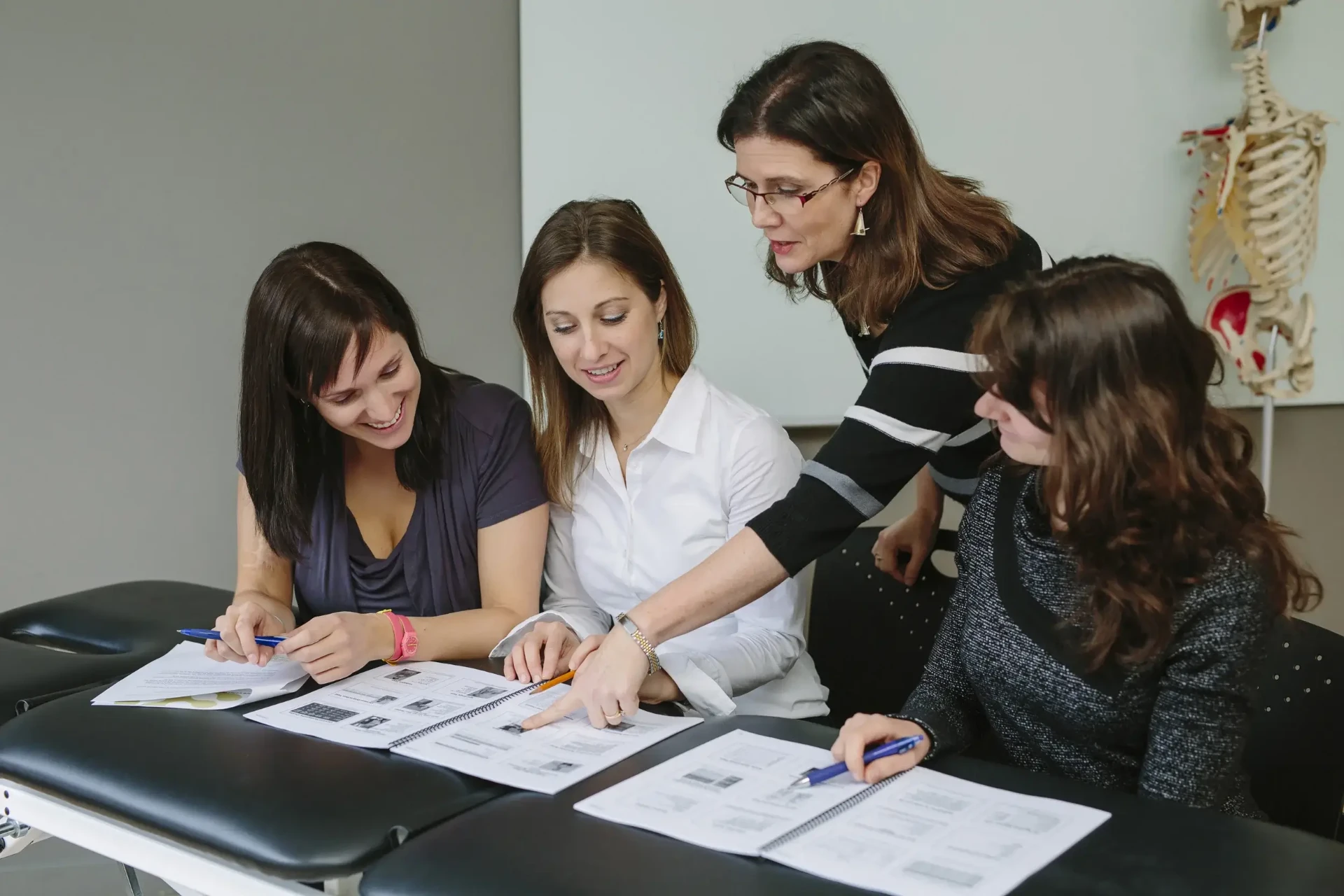 Enseignante accompagnant un groupe d'étudiantes sur les notes de cours.