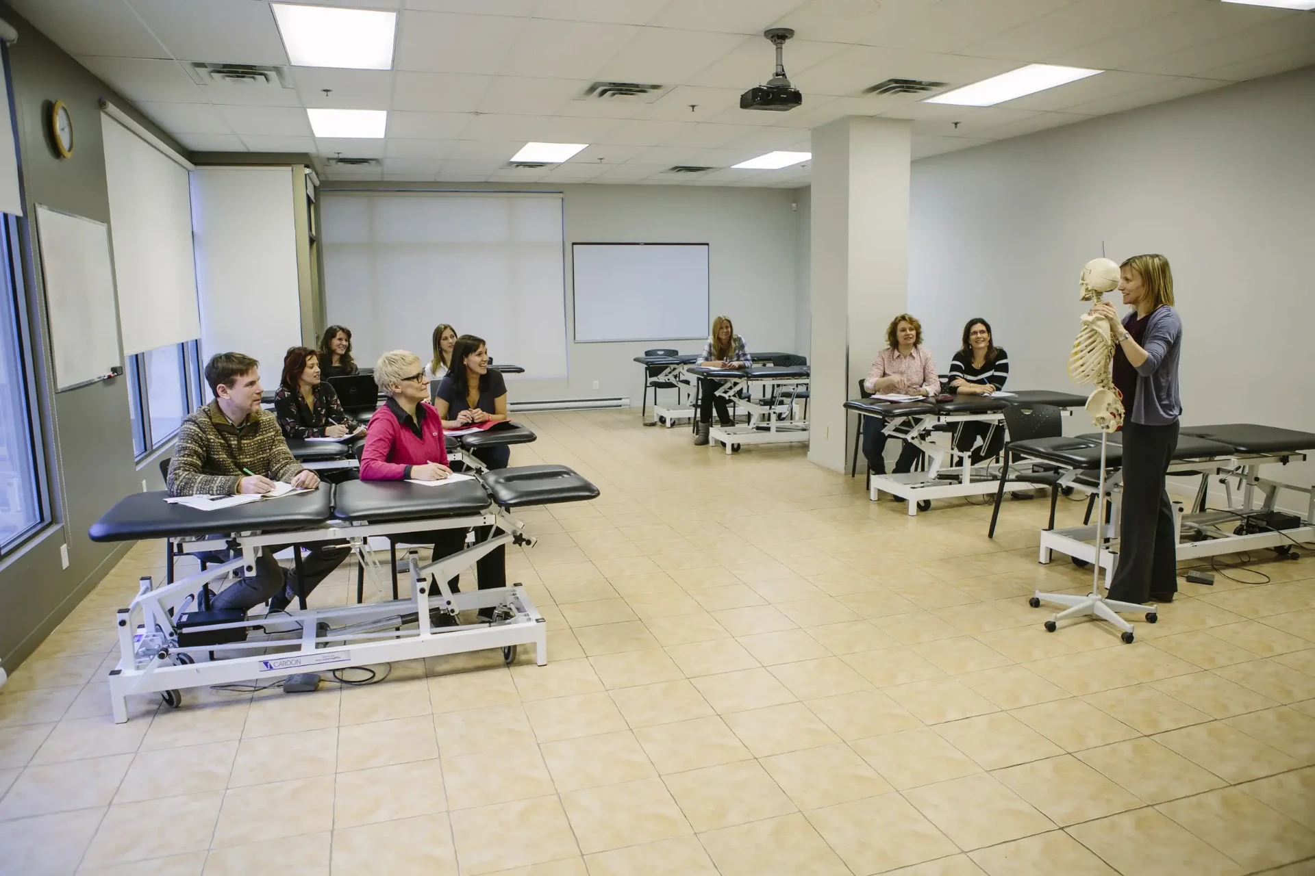 Salle de cours de Montréal avec tables de thérapie manuelle et démonstration au squelette.